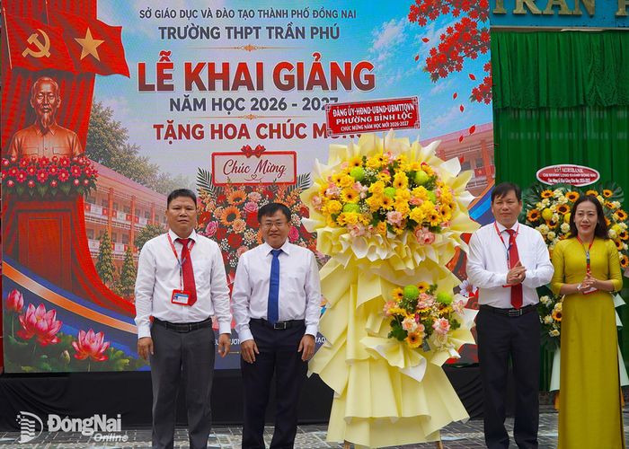Bí thư Đảng ủy, Chủ tịch HĐND phường Bình Lộc Nguyễn Xuân Hà thay mặt Đảng ủy, HĐND, UBND, Ủy ban MTTQ Việt Nam phường Bình Lộc tặng hoa chúc mừng nhà trường. Ảnh: An Nhơn