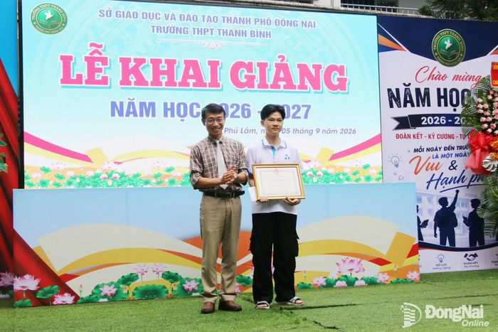 Bí thư Đảng ủy, Chủ tịch HĐND xã Phú Lâm Nguyễn Hữu Ký khen thưởng cho em Đào Thiên Ân, thủ khoa khối A00 của thành phố Đồng Nai trong kỳ thi tốt nghiệp THPT năm 2026. Ảnh: Hải Quân