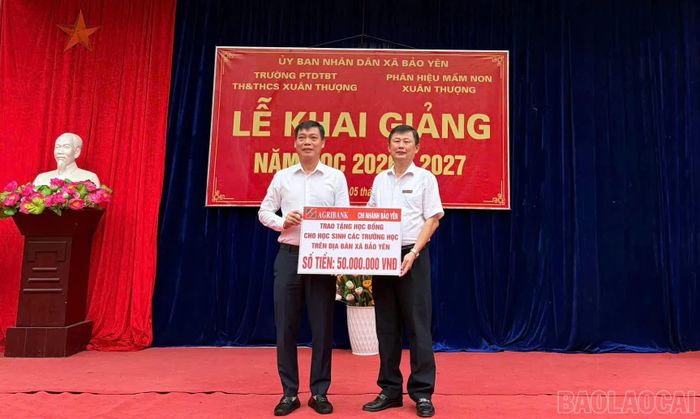 Đại diện Ngân hàng Nông nghiệp và PTNT Chi nhánh Bảo Yên trao bảng biểu trưng số tiền học bổng cho học sinh các trường trên địa bàn xã Bảo Yên.