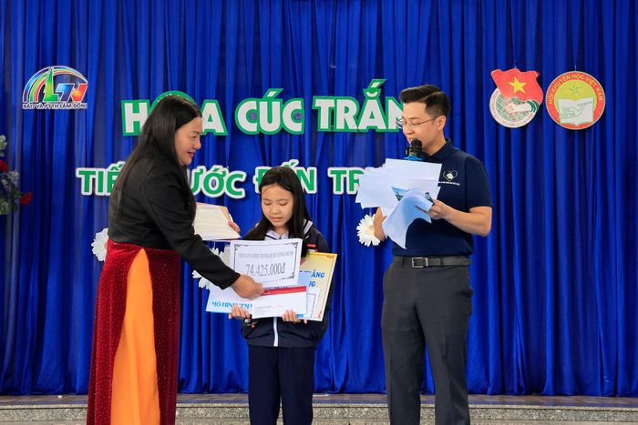 Cô Lê Thị Hậu, Phó Hiệu trưởng Trường Tiểu học Hùng Vương trao quà của Ban Giám hiệu và thầy cô giáo nhà trường cho em Thiên Kim.