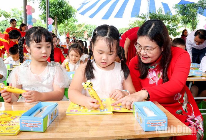 Đồng chí Hà Lan Anh, Tỉnh ủy viên, Phó Chủ tịch UBND tỉnh hướng dẫn các cháu Trường Mầm non Hoa Lư sử dụng bộ sách học tiếng Anh.