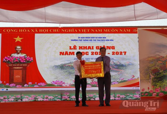 Đồng chí Nguyễn Đăng Quang, Phó Bí thư Tỉnh ủy, Chủ tịch HĐND tỉnh trao quà của đồng chí Tổng Bí thư, Chủ tịch nước Tô Lâm động viên, chúc mừng Trường phổ thông nội trú tiểu học và THCS Dân Hóa nhân dịp khai giảng năm học mới - Ảnh: X.P