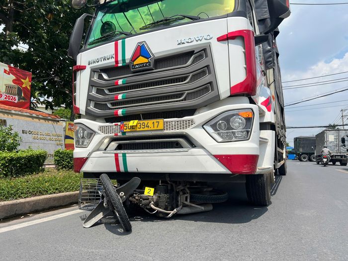 Chiếc xe máy bị cuốn vào gầm xe tải.