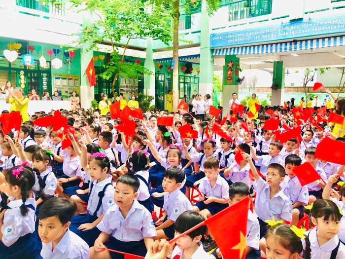 Các em học sinh vui mừng cầm lá cờ đỏ sao vàng trong ngày khai giảng.