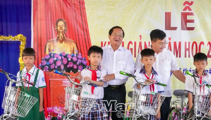 Phó Chủ tịch Thường trực Uỷ ban MTTQ Việt Nam tỉnh Cà Mau Lê Thanh Triều (bên trái) và Bí thư Đảng uỷ xã Tân Hưng Phan Thanh Liêm trao học bổng, tập và xe đạp cho đại diện Trường Tiểu học Tân Hưng và các em học sinh. 