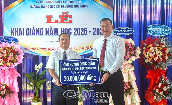 Giám đốc Sở Tài chính tỉnh Cà Mau Huỳnh Công Quân (bên phải) trao bảng tượng trưng tặng học bổng trị giá 20 triệu đồng cho học sinh có hoàn cảnh khó khăn.