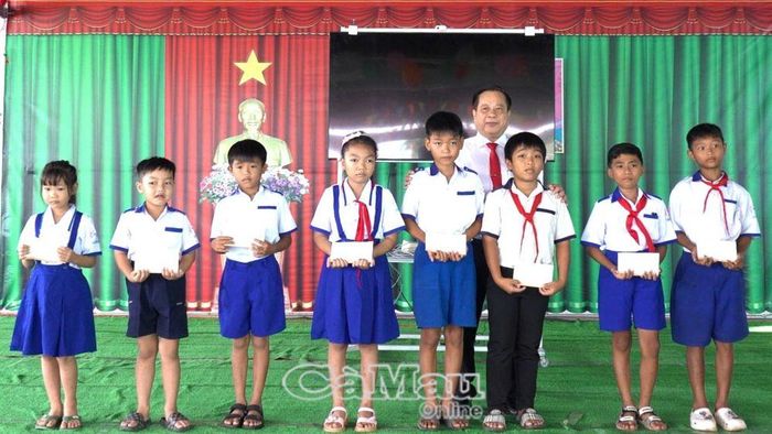 Ông Huỳnh Minh Nguyên, Bí thư Đảng uỷ, Chủ tịch HĐND xã Khánh Lâm, trao tập và học bổng cho học sinh Trường Tiểu học và THCS Trịnh Minh Hưởng nhân dịp khai giảng.