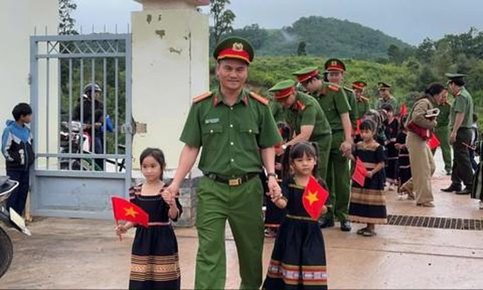 Thiếu tá Nguyễn Văn Hạnh, Trưởng Công an xã Tu Mơ Rông, cùng cán bộ, chiến sĩ Công an xã nắm tay đưa các em vào trường dự lễ khai giảng.