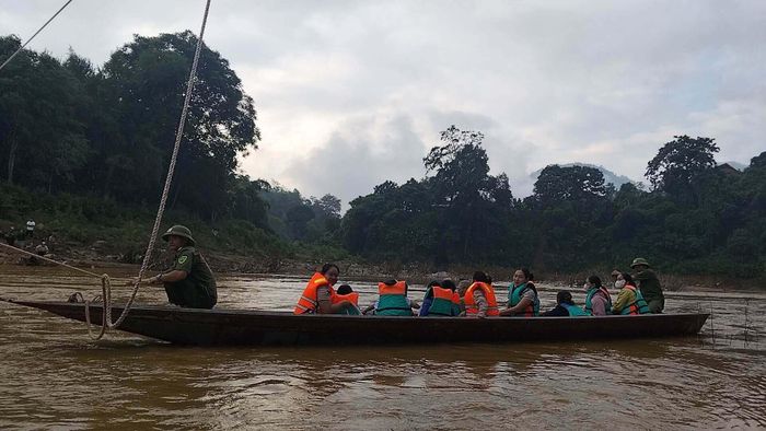 Lực lượng chức năng giăng dây, chèo thuyền đưa học sinh, các thầy cô qua sông. (Ảnh: Công an xã Yên Hòa)