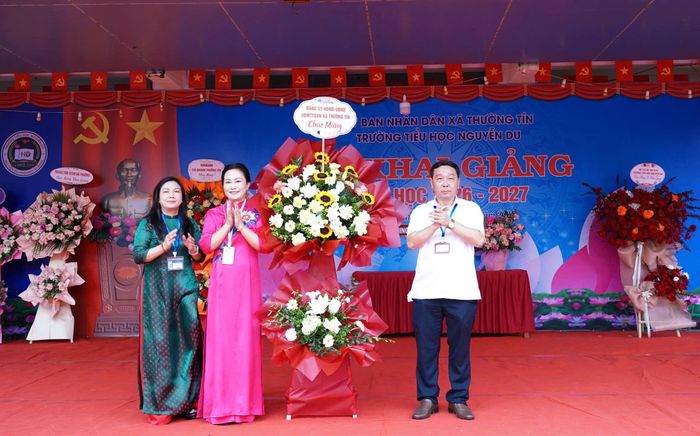 Ông Phan Thanh Tùng, Chủ tịch UBND xã Thường Tín, tặng hoa chúc mừng thầy và trò trường tiểu học Nguyễn Du nhân dịp khai giảng.