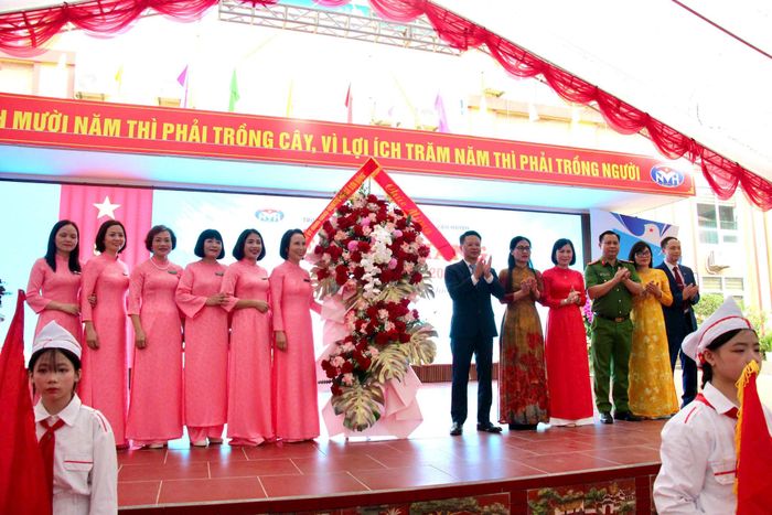 Lãnh đạo xã Sơn Đồng trao tặng lẵng hoa chúc mừng Trường THCS Nguyễn Văn Huyên. Ảnh: Bảo Lâm