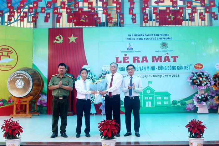 Bí thư Đảng ủy, Chủ tịch HĐND xã Đan Phượng Nguyễn Gia Hiển tặng hoa chúc mừng ra mắt mô hình “Trường học văn minh - Cộng đồng gắn kết” tại Trường THCS Đan Phượng. Ảnh: Thiên Tú