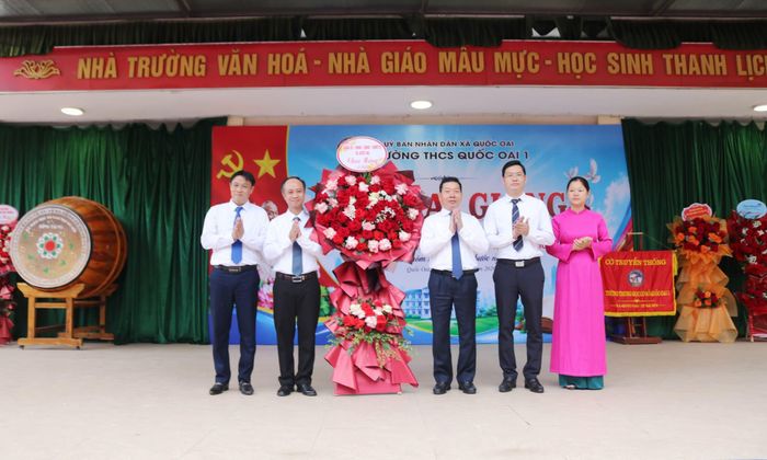Bí thư Đảng ủy xã Quốc Oai Nguyễn Trường Sơn tặng hoa chúc mừng thầy và trò Trường THCS Quốc Oai 1. Ảnh: PV