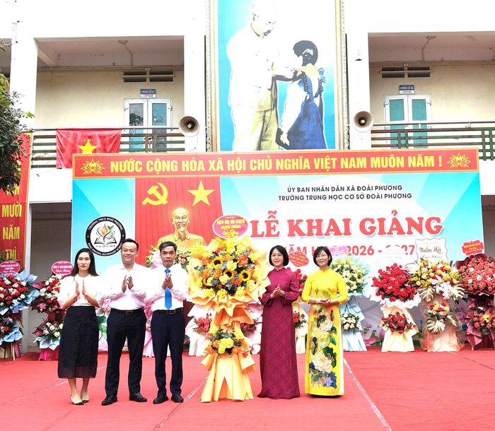 Bí thư Đảng ủy, Chủ tịch HĐND xã Đoài Phương Nguyễn Quang Hán tặng hoa chúc mừng Trường THCS Đoài Phương. Ảnh: PV