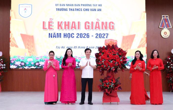 Phó Bí thư Thường trực Đảng uỷ phường Tây Hồ Lê Quốc Thịnh dự và tặng hoa chúc mừng trường Tiểu học và THCS Chu Văn An. Ảnh: Hà Phương 
