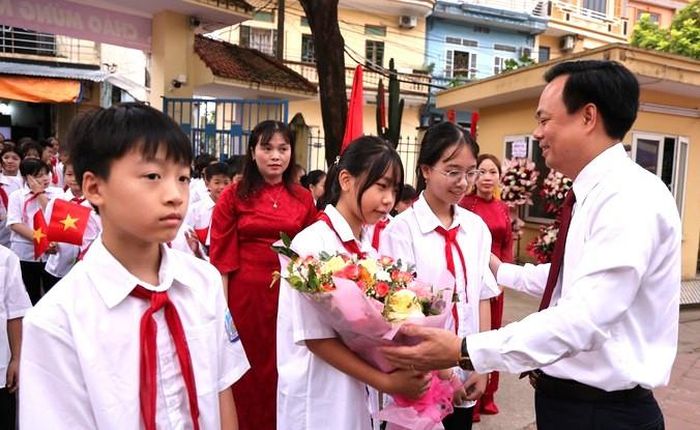 Chủ tịch UBND xã Tam Hưng Bùi Đình Thái tặng hoa chúc mừng và động viên học sinh lớp 6 Trường THCS Tam Hưng 1. Ảnh: Bình Minh