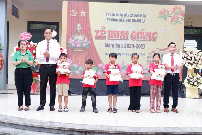 Phó Bí thư Thường trực Đảng ủy xã Hát Môn Dương Chí Thanh tặng quà cho các em học sinh Trường Tiểu học Thanh Đa nhân ngày khai trường. Ảnh: HM