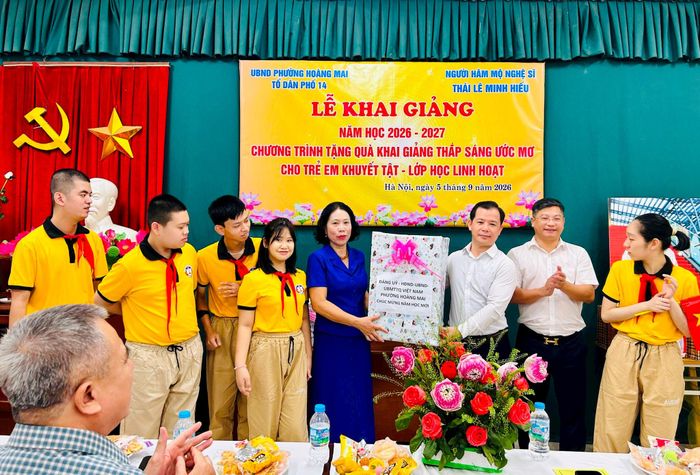 Chủ tịch Ủy ban MTTQ Việt Nam phường Hoàng Mai Triệu Hải Vân trao quà cho các em học sinh và cô giáo lớp học Linh hoạt. Ảnh: Trần Oanh.