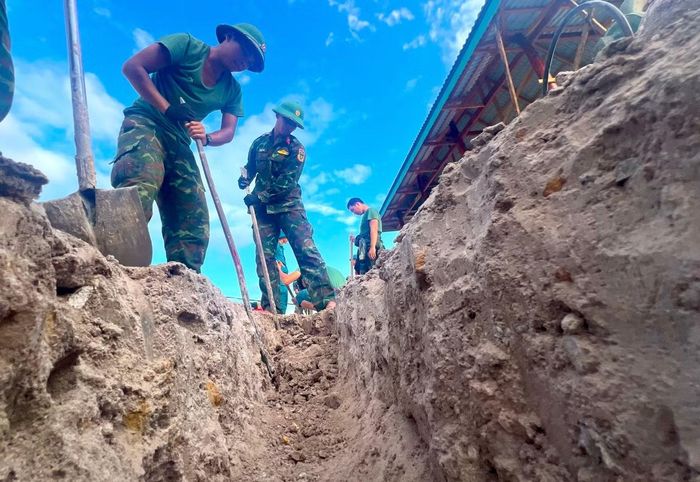 Thiếu tá Nguyễn Công Sáu - Trợ lý Ban Chính trị Trung đoàn 991, Bộ Chỉ huy Quân sự tỉnh Gia Lai cùng các chiến sĩ đang đào mương hệ thống thoát nước tại nơi ở mới cho bà con.