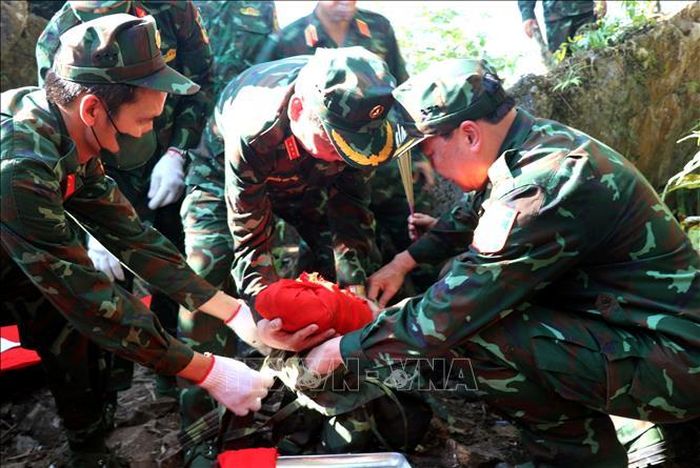 Cán bộ, chiến sĩ nhẹ nhàng, nâng niu đưa hài cốt liệt sĩ vừa tìm thấy về nơi quy tập. Ảnh: Đức Thọ/TTXVN