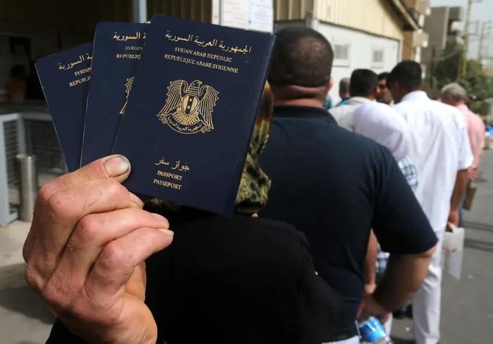Một người đàn ông Syria cầm hộ chiếu của các thành viên trong gia đình khi xếp hàng cùng những người Syria khác để làm thủ tục xin thị thực tị nạn bên ngoài Đại sứ quán Đức tại Beirut, Lebanon. Ảnh: AP.