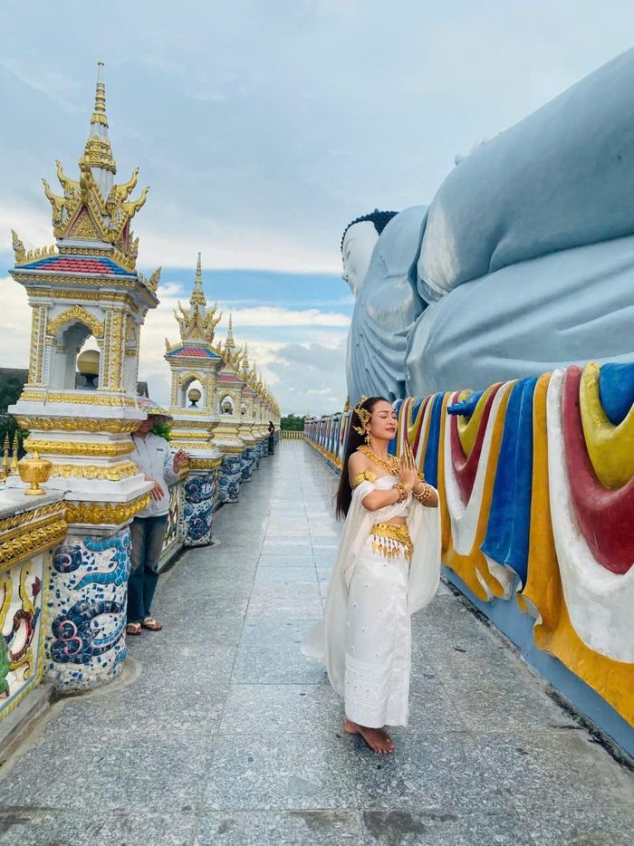 Cô gái trong trang phục truyền thống của dân tộc Khmer chụp ảnh lưu niệm cùng tượng Phật nằm chùa Som Rong