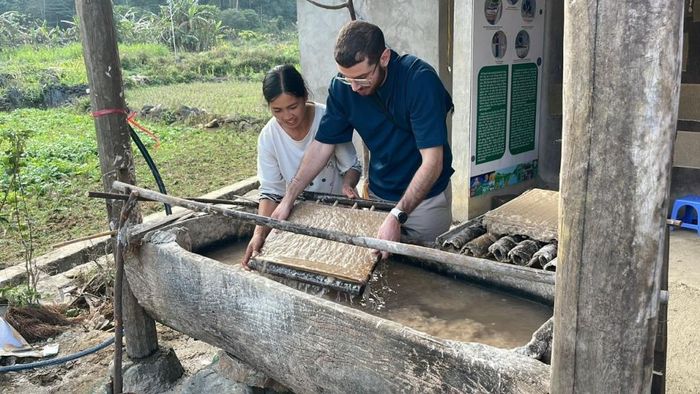 Chị Nông Thị Xanh hướng dẫn khách nước ngoài thực hiện công đoạn xeo giấy bản truyền thống.
