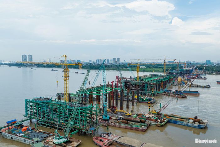 Công trường cầu Trần Hưng Đạo sôi động hơn thường lệ. Máy móc, thiết bị hoạt động liên tục, những khối thép nặng hàng chục tấn được vận chuyển, lắp dựng giữa sông Hồng. Ảnh: PV