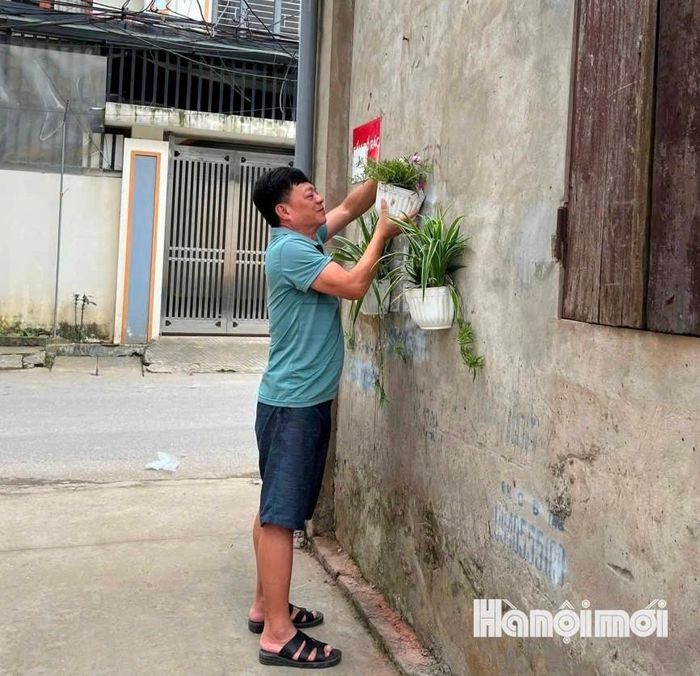 Ông Nguyễn Đức Long, Bí thư Chi bộ tổ dân phố Nhật Tảo 1 treo giỏ hoa, góp phần tạo cảnh quan xanh, đẹp cho khu dân cư. Ảnh: Diên Vĩ