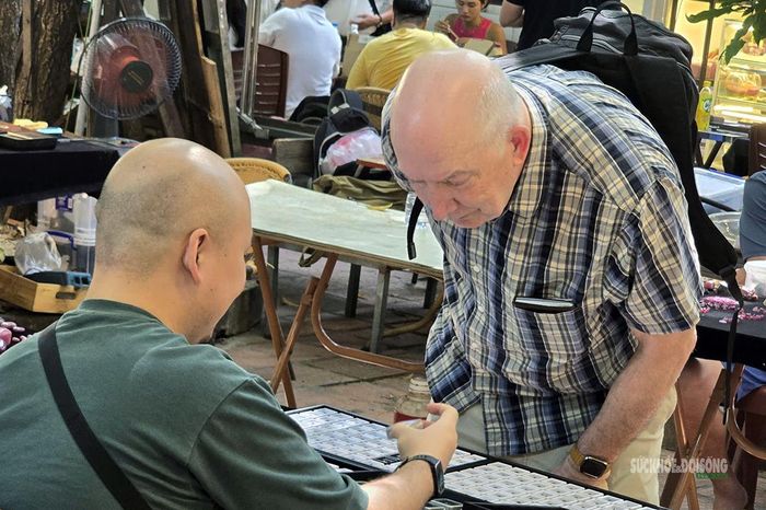 Một du khách nước ngoài cúi sát quầy để lựa đá. Ảnh: T.Anh