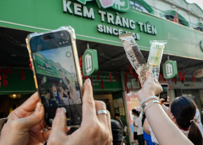  Với chị Dương Quyên (phải, phường Phú Lương), Kem Tràng Tiền là một trong những thức quà vặt tuổi thơ yêu thích. "Tôi ăn ở đây hơn 30 năm rồi, từ ngày chỉ có những vị cơ bản như đậu xanh, vani, cacao, giờ thì các hương vị đa dạng hơn nhiều. Tôi chưa từng mua kem ở các cơ sở khác, không biết vị có khác biệt gì không, có lẽ sau ngày 15/9, tôi sẽ ăn thử xem sao. Còn hôm nay, có lẽ là lần cuối chúng tôi đến đây nên tranh thủ ăn nốt", chị cho hay.