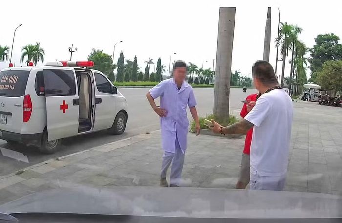 Hình ảnh người đàn ông mặc áo blouse trắng đi cùng xe cấp cứu, đưa bệnh nhân về nhà. Ảnh cắt từ clip.