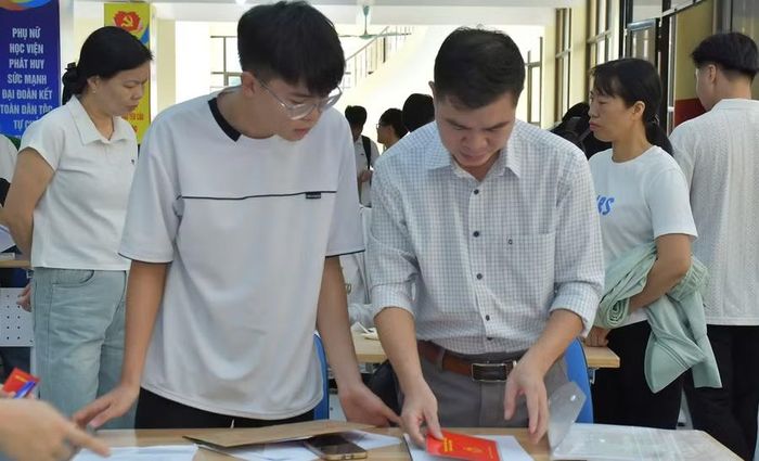 Tân sinh viên được phụ huynh hỗ trợ, sắp xếp giấy tờ trước khi làm thủ tục nhập học trực tiếp.