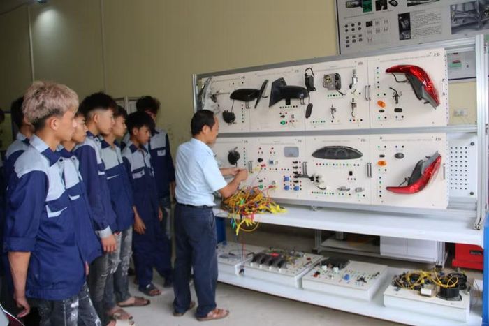 Sinh viên ngành công nghệ ô tô chăm chú theo dõi giảng viên hướng dẫn thực hành.