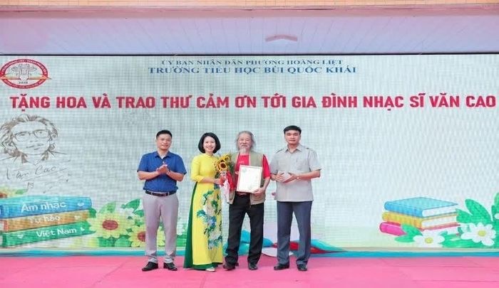 Đại diện Trường Tiểu học Bùi Quốc Khái tặng hoa và trao thư cảm ơn tới nghệ sĩ Văn Thao. (Ảnh: Huệ Chi)