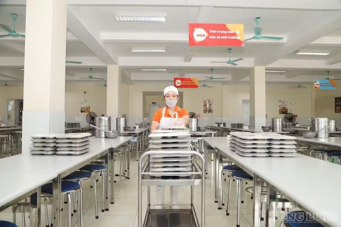 Nhân viên bếp ăn bắt đầu thực hiện chia suất cơm ra từng khu vực ăn của học sinh.
