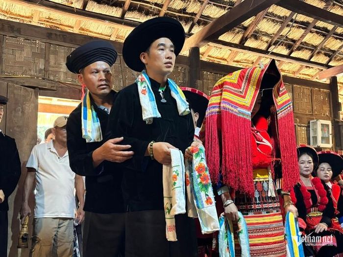 Cô dâu, chú rể người Dao đỏ đứng trước bàn thờ gia tiên để ông quan lang và hai ông phụ lễ làm thủ tục trong ngày cưới