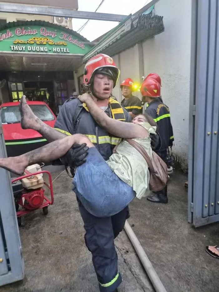 Một chiến sỹ Phòng cháy chữa cháy và Cứu nạn cứu bế một nạn nhân nữ đang bị ngạt khói từ tầng 4 xuống dưới đất. (Ảnh: CTV/Vietnam+)