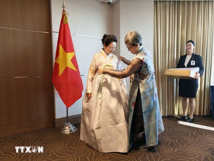 Nghệ nhân áo truyền thống Hanbok tặng áo thiết kế cho Phu nhân Nguyễn Thị Thanh Nga. (Ảnh: Đào Lâm/TTXVN)