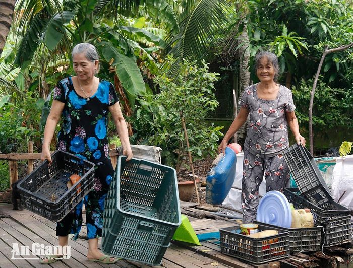 Bà Lê Thị Thoại (bên phải) tự giác di dời vật dụng lấn chiếm phần đất thuộc khu vực quy hoạch mở rộng Cảng hàng không Rạch Giá. Ảnh: DANH THÀNH