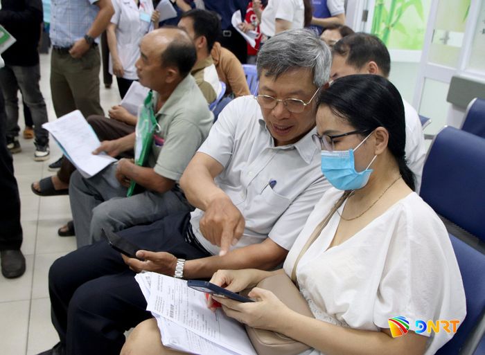 Phó Chủ tịch UBND thành phố Hồ Quang Bửu chia sẻ trải nghiệm app OneCare với một người dân đến khám bệnh. Ảnh: TRỌNG HUY