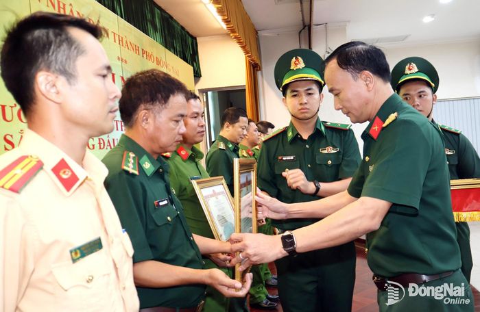 Đại tá Võ Thành Danh, Ủy viên Ban Thường vụ Thành ủy, Chỉ huy trưởng Bộ Chỉ huy Quân sự thành phố trao bằng khen cho các cá nhân. Ảnh: Nguyệt Hà