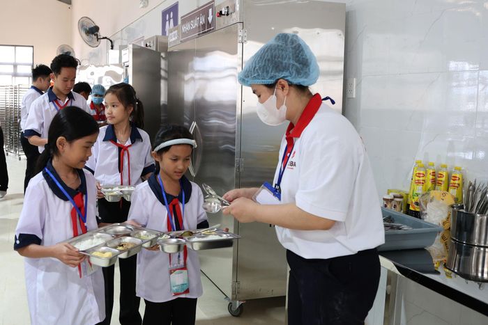 Học sinh nhận khay đồ ăn từ nhân viên cấp dưỡng