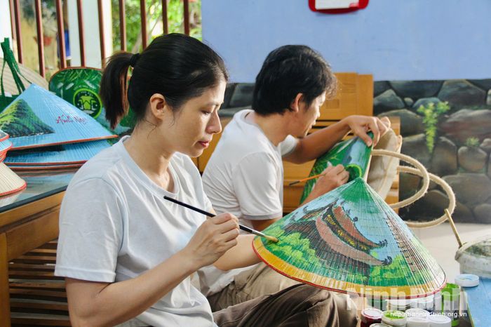 Chị Lã Phương Hằng tỉ mỉ vẽ từng đường nét trên nón lá.