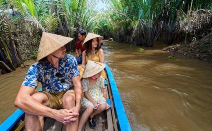 Du khách đội nón lá, ngồi trên xuồng xuôi theo con nước Miền Tây