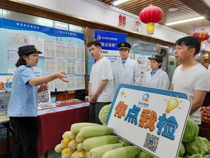 Cán bộ kiểm tra an toàn thực phẩm tại chợ nông sản cùng người tiêu dùng chọn mẫu. Ảnh: Bjdch.gov.cn