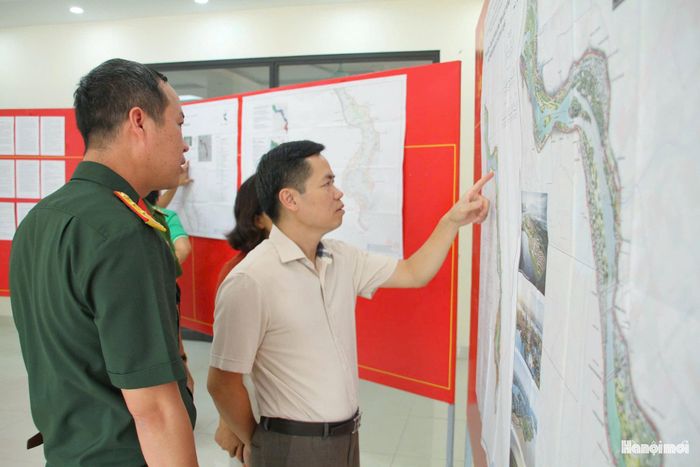 Trưởng phòng Kinh tế, Hạ tầng và Đô thị phường Phú Thượng Nguyễn Quang Ngọc (áo trắng) kiểm tra công tác niêm yết hồ sơ Quy hoạch phân khu đô thị sông Hồng. Ảnh: Cao Kỳ