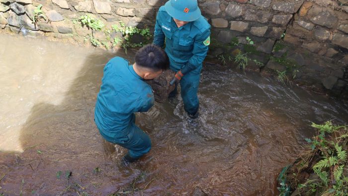  Khiêng đá giữa mương nước để gia cố bờ. Ảnh: HỮU PHÚC 