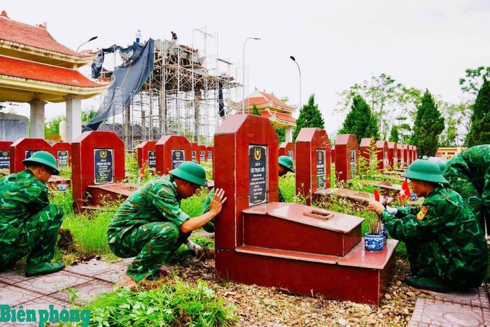 Cán bộ, chiến sĩ Trường Trung cấp 24 Biên phòng tham gia dọn vệ sinh các phần mộ tại Nghĩa trang liệt sĩ Vật Lại. Ảnh: Xuân Hải