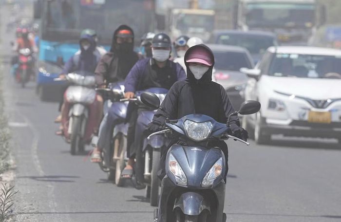 Hàng dài người lái xe máy lưu thông dưới chân cầu Thăng Long phải đeo khẩu trang và đội mũ trùm kín mặt để bảo vệ hệ hô hấp khỏi bụi mịn.